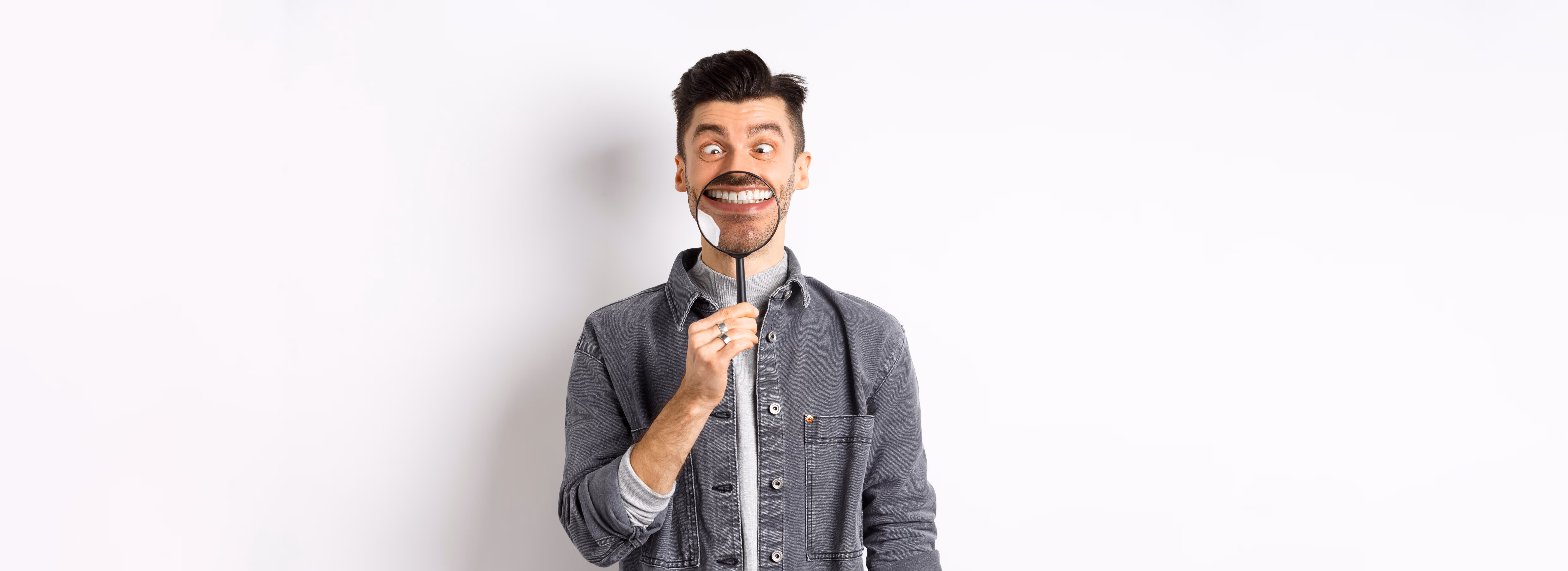 虫眼鏡で自分を見る笑顔の男性