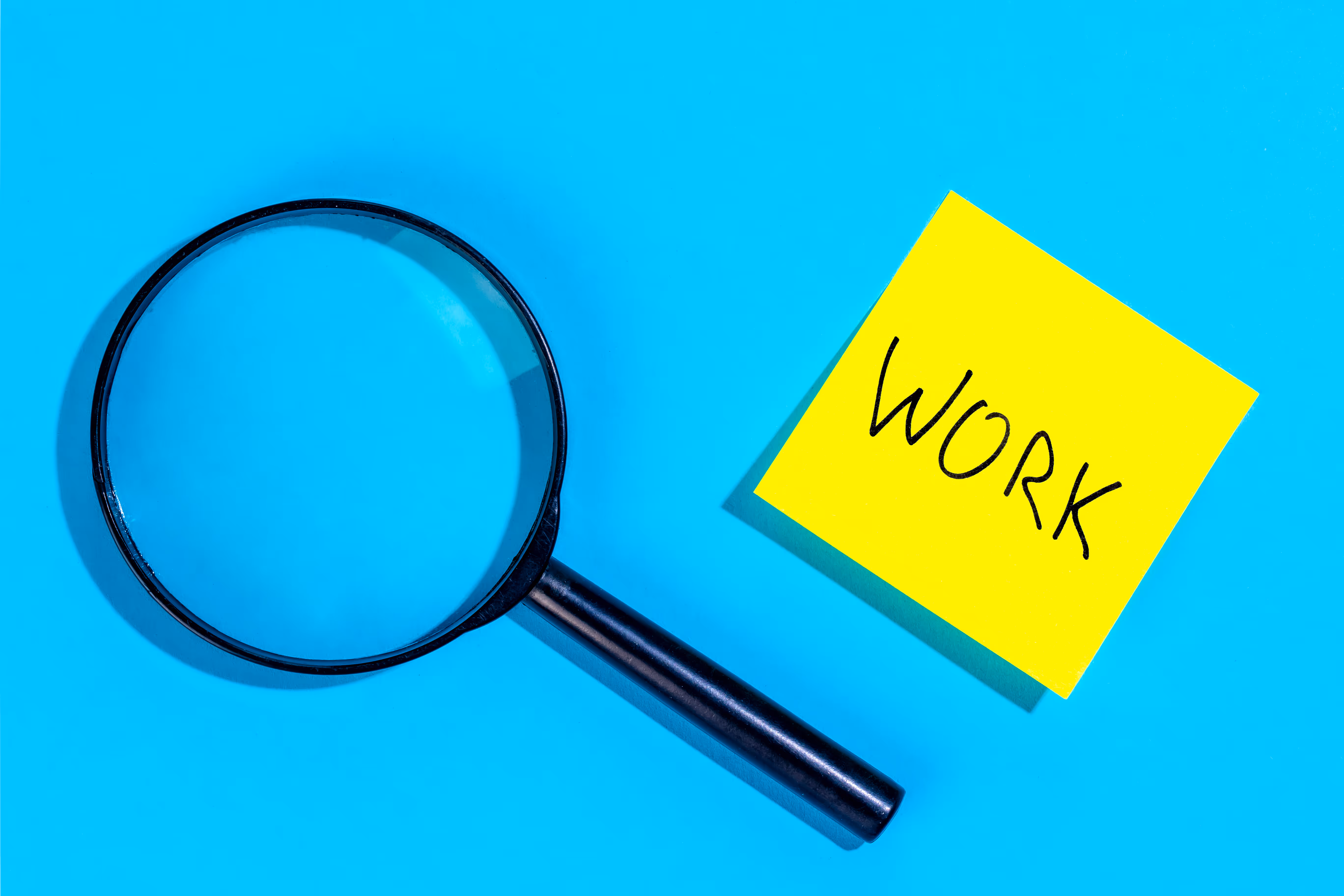 青背景で付箋を虫眼鏡越しに見る