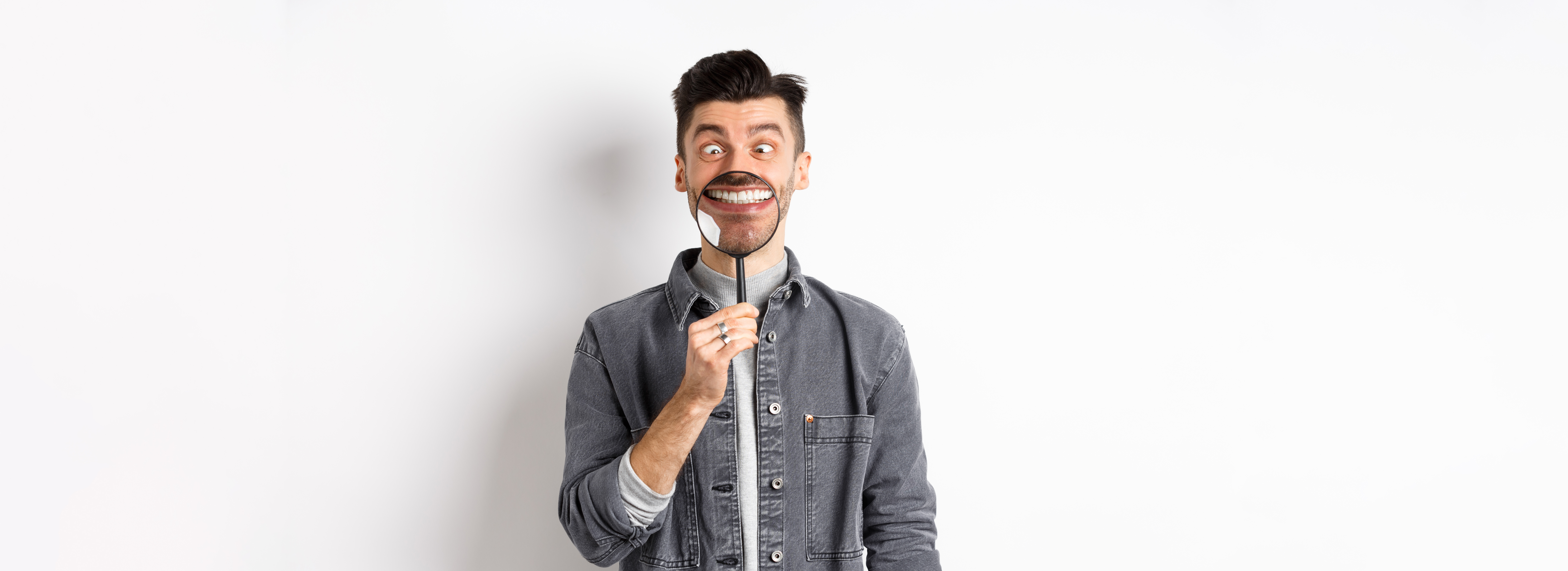 虫眼鏡で自分を見る笑顔の男性