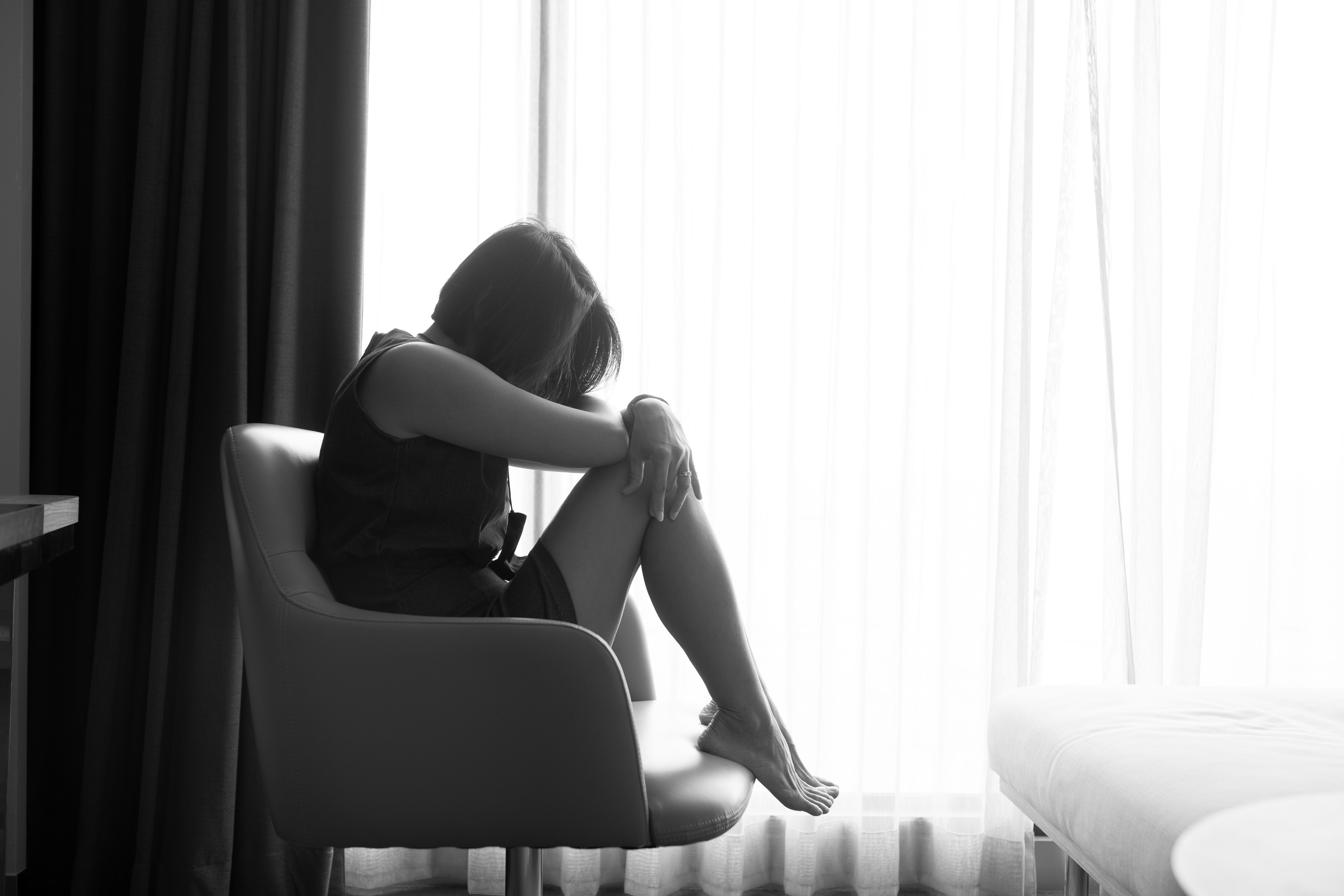 窓際でうつむく女性